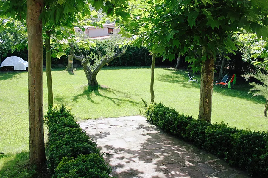 Camino entre árboles en el jardín de Casa Larrate